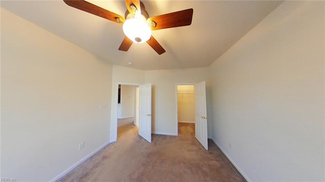 unfurnished bedroom featuring a walk in closet, ceiling fan, a closet, and light carpet