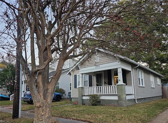 bungalow featuring covered porch and a front yard