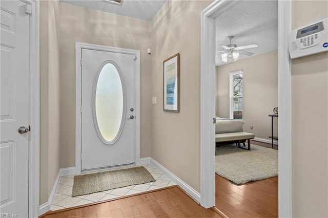 foyer entrance featuring a textured ceiling, light wood-type flooring, and ceiling fan