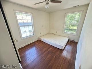 unfurnished bedroom featuring dark hardwood / wood-style flooring, multiple windows, and ceiling fan