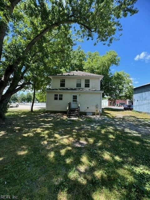 rear view of property featuring a lawn