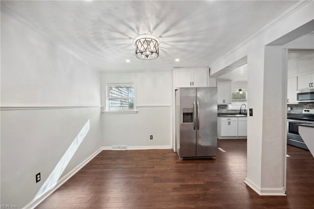 kitchen with tasteful backsplash, white cabinets, dark wood-type flooring, and appliances with stainless steel finishes