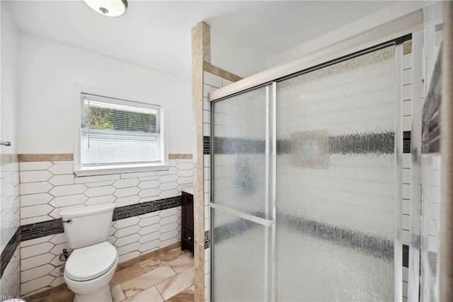 bathroom featuring walk in shower, toilet, and tile walls