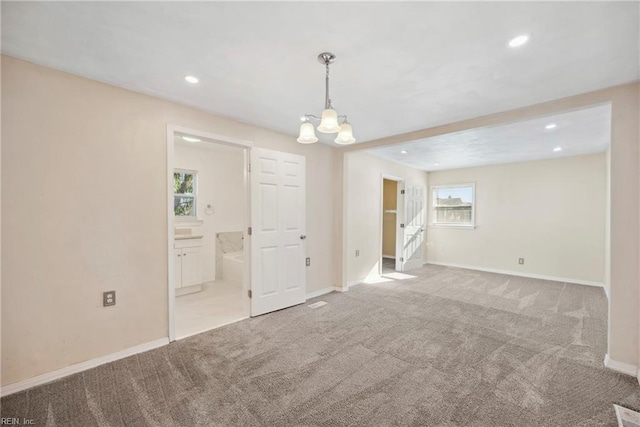 unfurnished room with light colored carpet and a notable chandelier