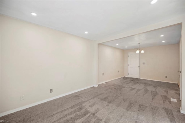 carpeted empty room featuring an inviting chandelier