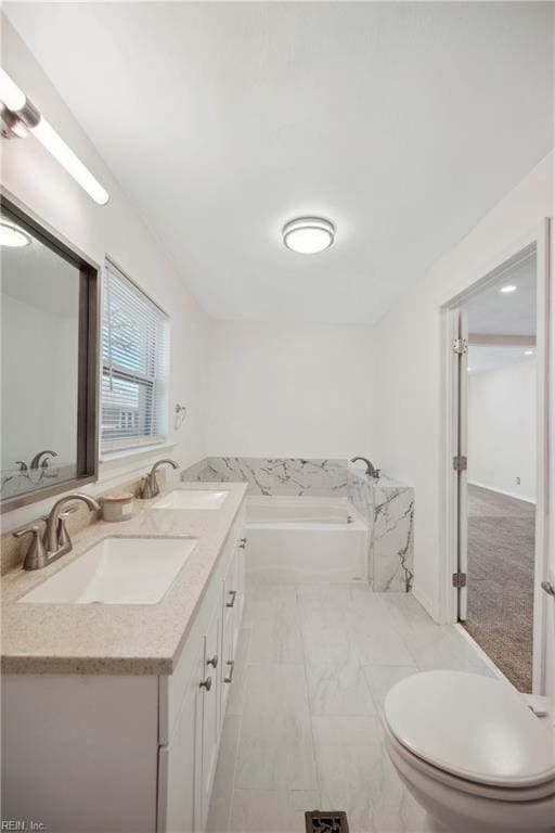 bathroom with a washtub, vanity, and toilet