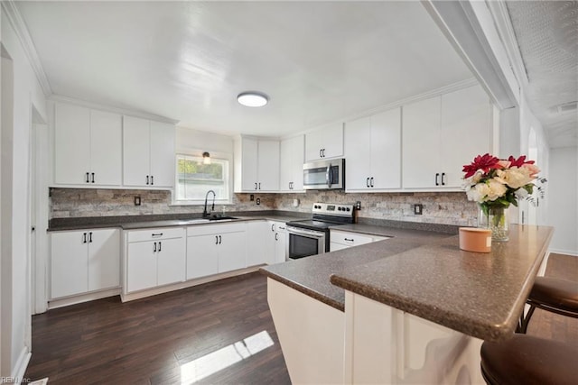 kitchen featuring sink, kitchen peninsula, dark hardwood / wood-style floors, white cabinetry, and stainless steel appliances