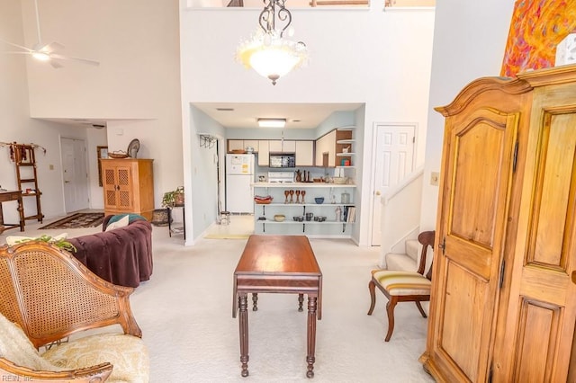 living room featuring ceiling fan, a towering ceiling, and light colored carpet