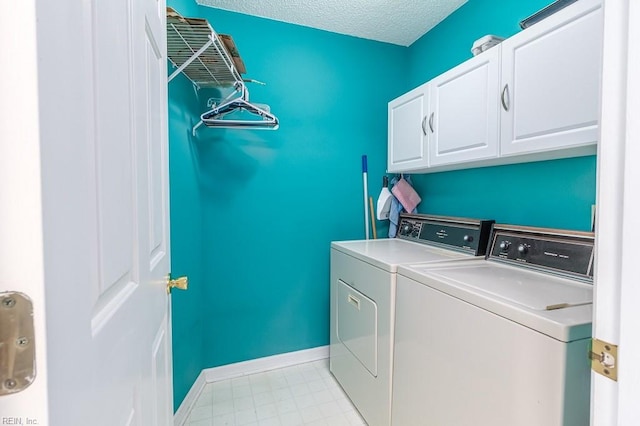 clothes washing area featuring cabinets, a textured ceiling, and washer and clothes dryer