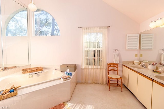 bathroom with vanity, tiled bath, and vaulted ceiling