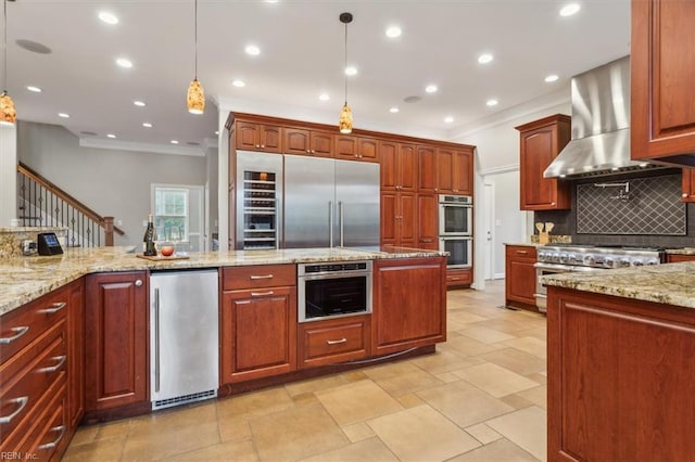 kitchen featuring wall chimney exhaust hood, premium appliances, tasteful backsplash, light stone counters, and decorative light fixtures