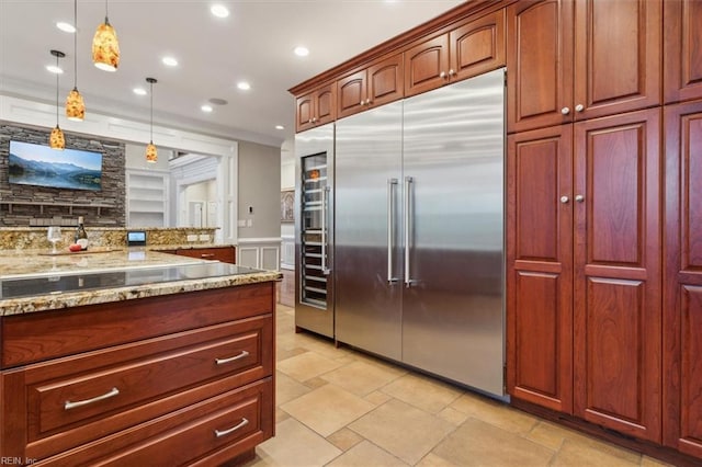 kitchen featuring tasteful backsplash, light stone counters, decorative light fixtures, black electric cooktop, and stainless steel built in fridge