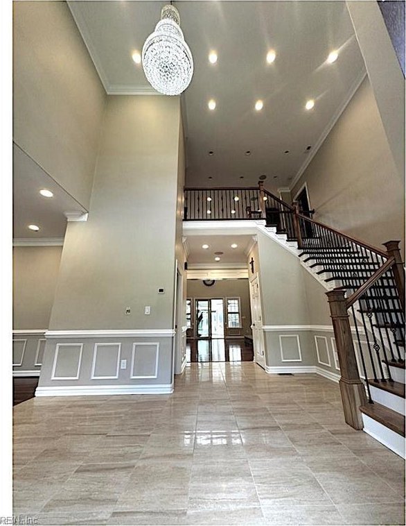 stairway with ornamental molding and a chandelier
