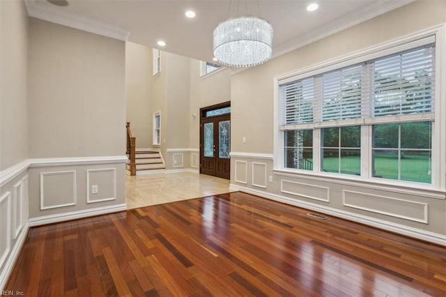 interior space with hardwood / wood-style floors, ornamental molding, french doors, and a notable chandelier