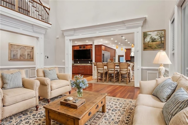 living room featuring a high ceiling, light wood-type flooring, and ornamental molding