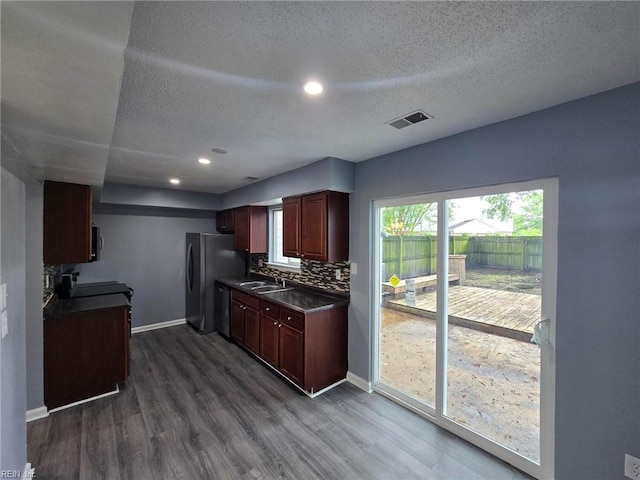 kitchen featuring dishwasher, sink, dark hardwood / wood-style floors, backsplash, and stainless steel fridge