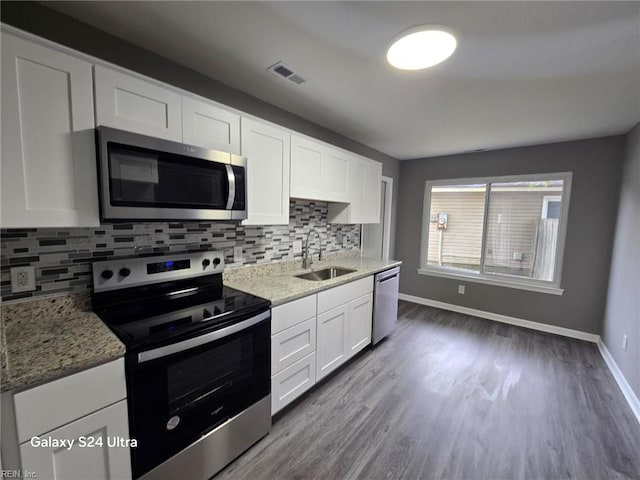 kitchen with decorative backsplash, appliances with stainless steel finishes, dark wood-type flooring, sink, and white cabinets