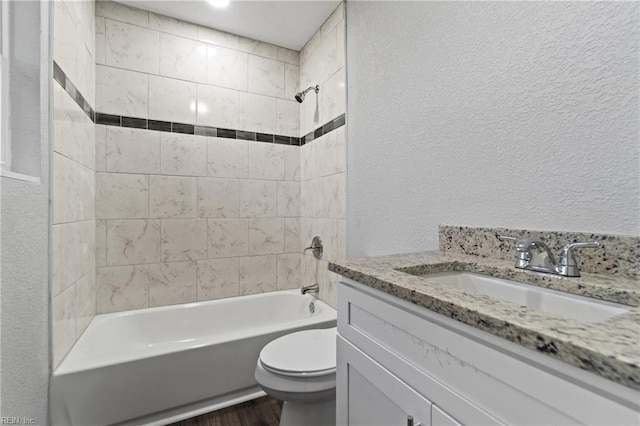 full bathroom with hardwood / wood-style flooring, vanity, toilet, and tiled shower / bath