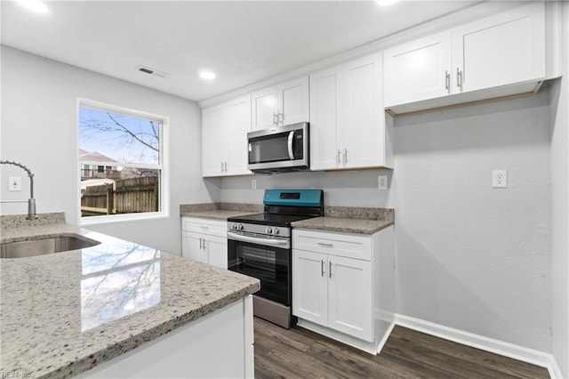 kitchen featuring white cabinets, stainless steel appliances, light stone counters, and sink