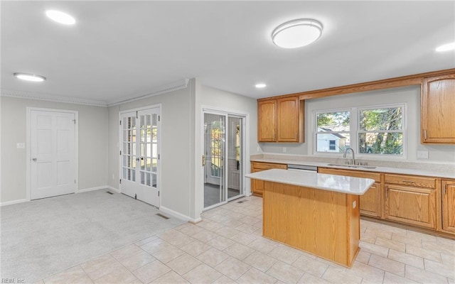 kitchen with light carpet, a kitchen island, ornamental molding, and sink