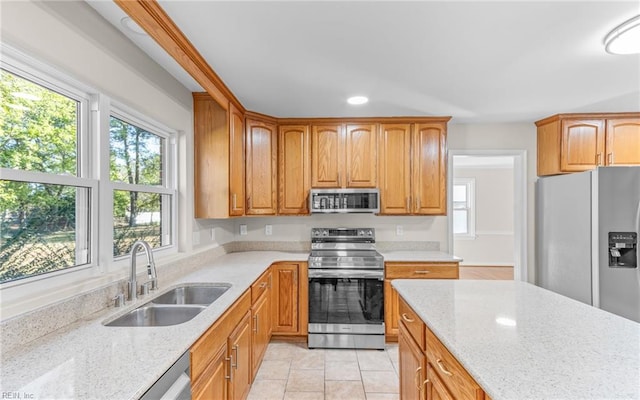 kitchen with light stone counters, sink, and appliances with stainless steel finishes