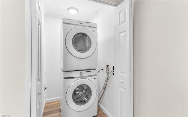 laundry area featuring stacked washer / drying machine and light wood-type flooring