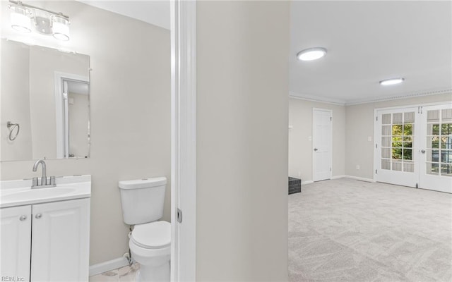 bathroom with vanity, toilet, crown molding, and french doors