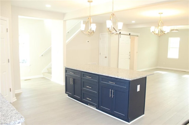 kitchen featuring pendant lighting, a barn door, light hardwood / wood-style floors, and a center island