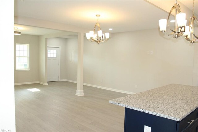 unfurnished dining area with hardwood / wood-style floors and an inviting chandelier