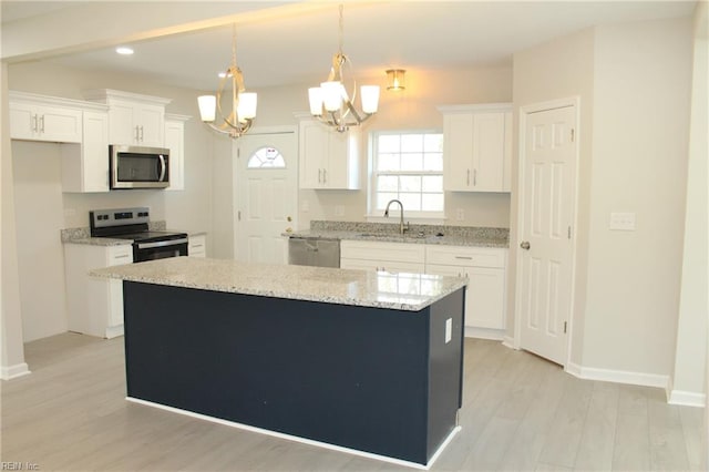 kitchen featuring white cabinetry, a center island, a chandelier, decorative light fixtures, and appliances with stainless steel finishes