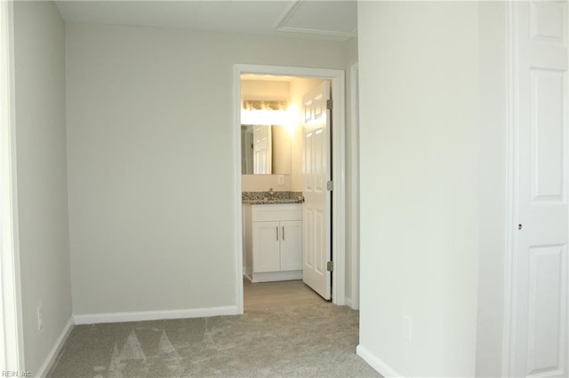 corridor featuring light carpet and sink