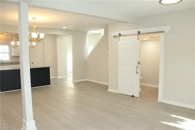 basement with a chandelier, a barn door, and light hardwood / wood-style flooring