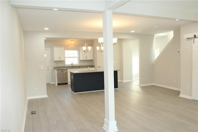 kitchen with white cabinetry, a kitchen island, a chandelier, and light wood-type flooring