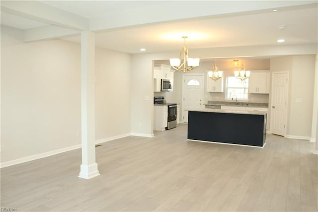 kitchen with appliances with stainless steel finishes, light wood-type flooring, pendant lighting, a center island, and white cabinetry