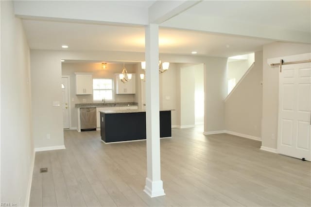 kitchen with white cabinets, a barn door, light hardwood / wood-style floors, and a notable chandelier