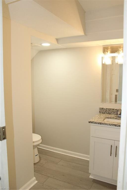 bathroom featuring toilet, vanity, and hardwood / wood-style flooring