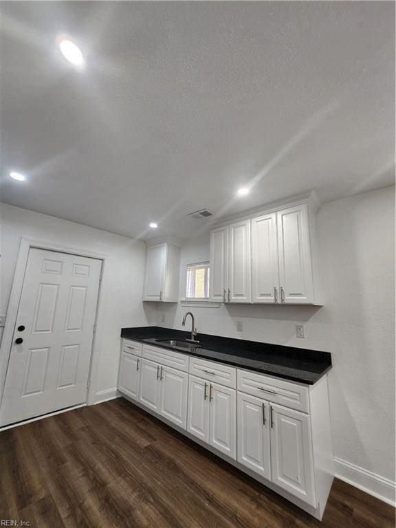 kitchen featuring white cabinetry, dark hardwood / wood-style flooring, a textured ceiling, and sink