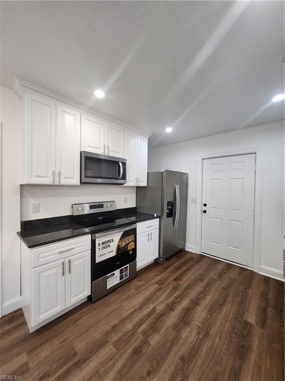 kitchen with white cabinets, appliances with stainless steel finishes, and dark wood-type flooring