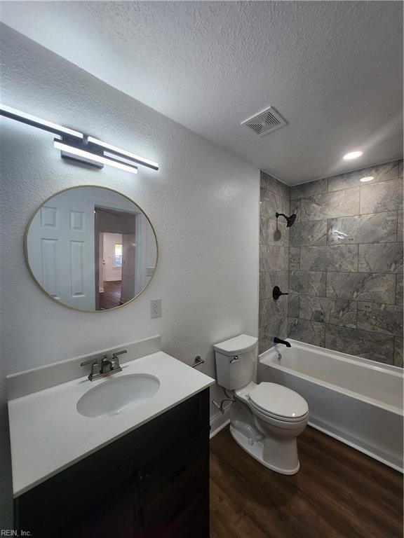 full bathroom featuring vanity, hardwood / wood-style floors, tiled shower / bath combo, and a textured ceiling