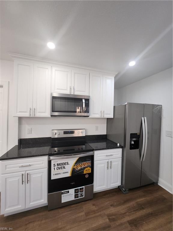 kitchen featuring dark stone countertops, white cabinetry, stainless steel appliances, and dark wood-type flooring