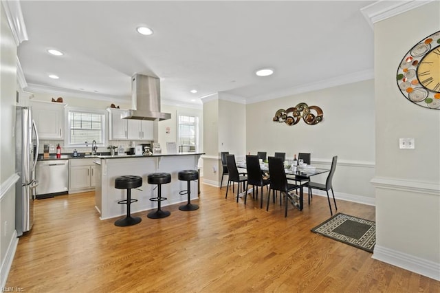 kitchen featuring white cabinetry, a center island, island exhaust hood, light hardwood / wood-style floors, and appliances with stainless steel finishes