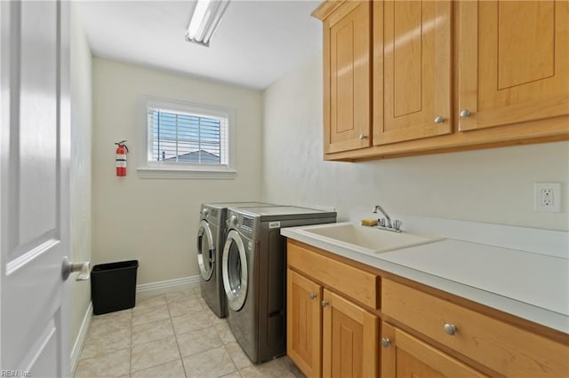 clothes washing area with cabinets, independent washer and dryer, light tile patterned floors, and sink