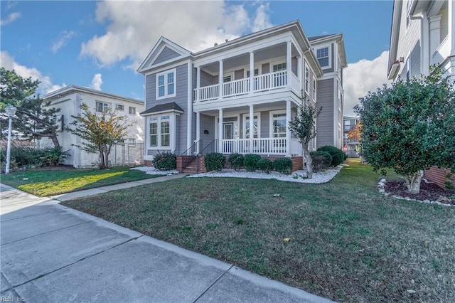 view of front of house with a porch, a balcony, and a front yard