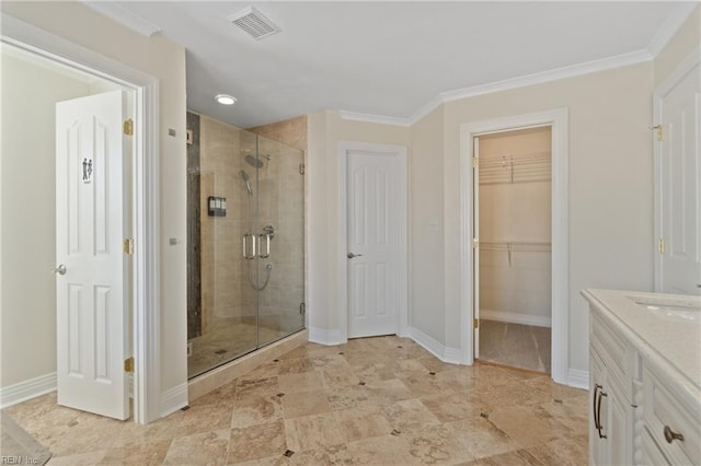 bathroom featuring vanity, a shower with shower door, and ornamental molding