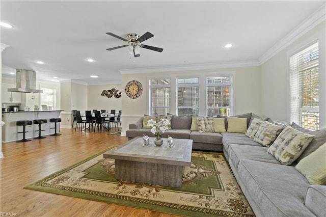 living room featuring a wealth of natural light, ornamental molding, and light wood-type flooring