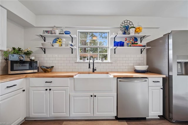 kitchen featuring white cabinets, butcher block counters, sink, and appliances with stainless steel finishes