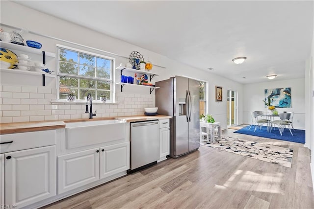 kitchen featuring white cabinets, sink, appliances with stainless steel finishes, and light hardwood / wood-style flooring