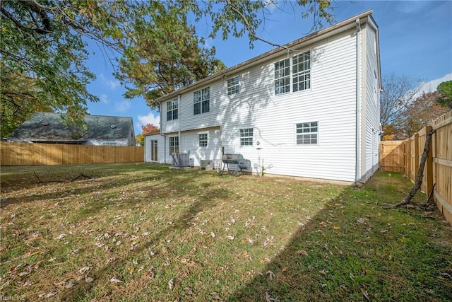 rear view of house with a lawn and central AC