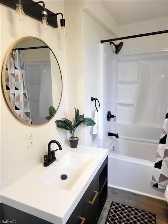 bathroom with hardwood / wood-style flooring, vanity, and shower / tub combo