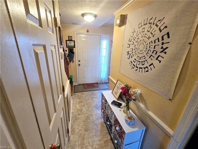 foyer entrance featuring ornamental molding and a textured ceiling